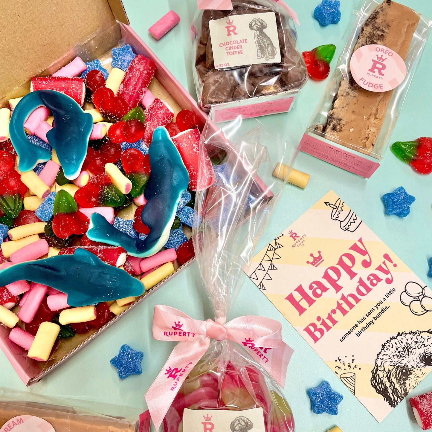 Birthday pick and mix box open to show the sweets you get inside, with a bar of clotted cream fudge, oreo fudge, small bag of chocolate cinder toffee, small bag of vegan giant strawberries and a happy birthday marketing card- Rupert's Candy