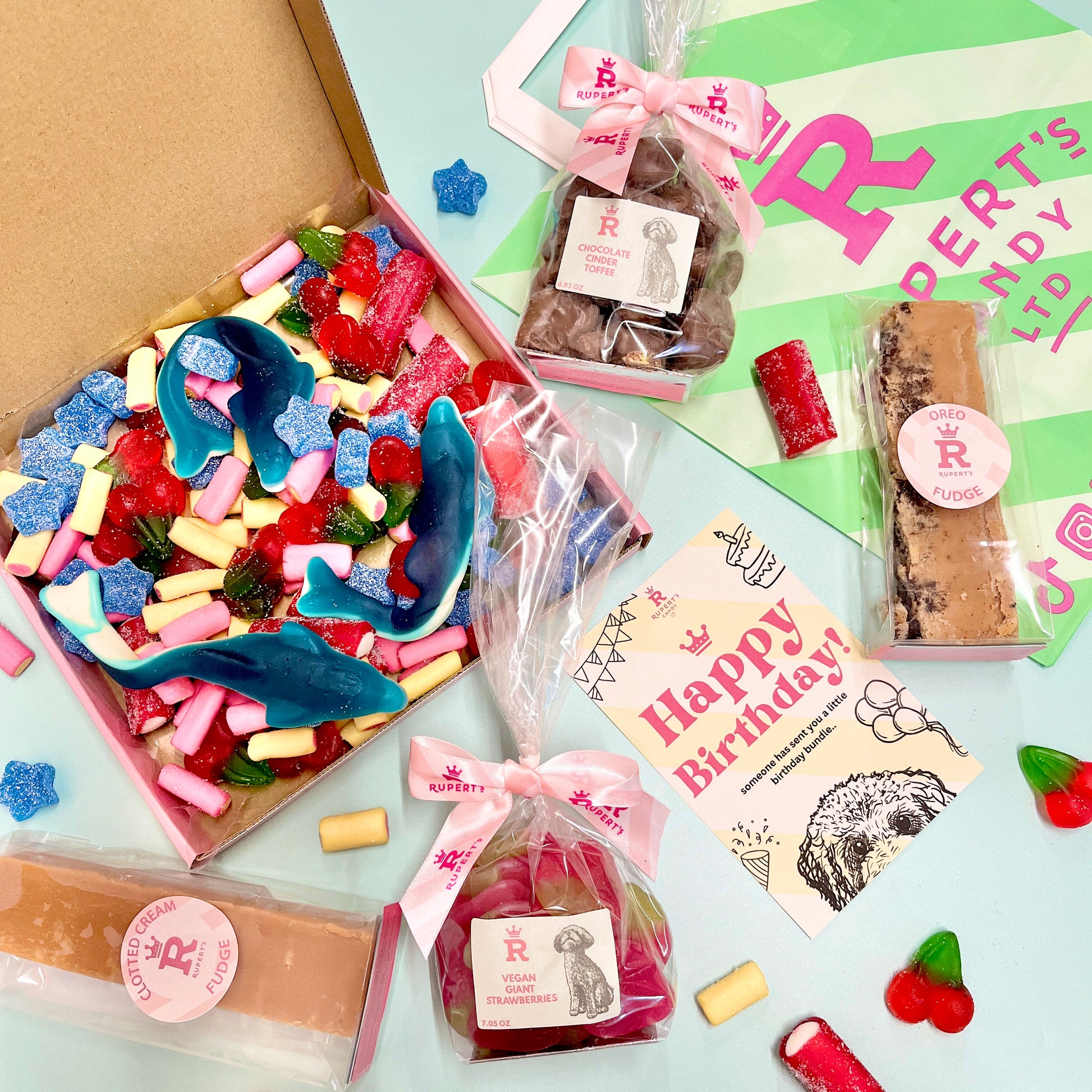 Birthday pick and mix box open to show the sweets you get inside, with a bar of clotted cream fudge, oreo fudge, small bag of chocolate cinder toffee, small bag of vegan giant strawberries and a happy birthday marketing card- Rupert's Candy