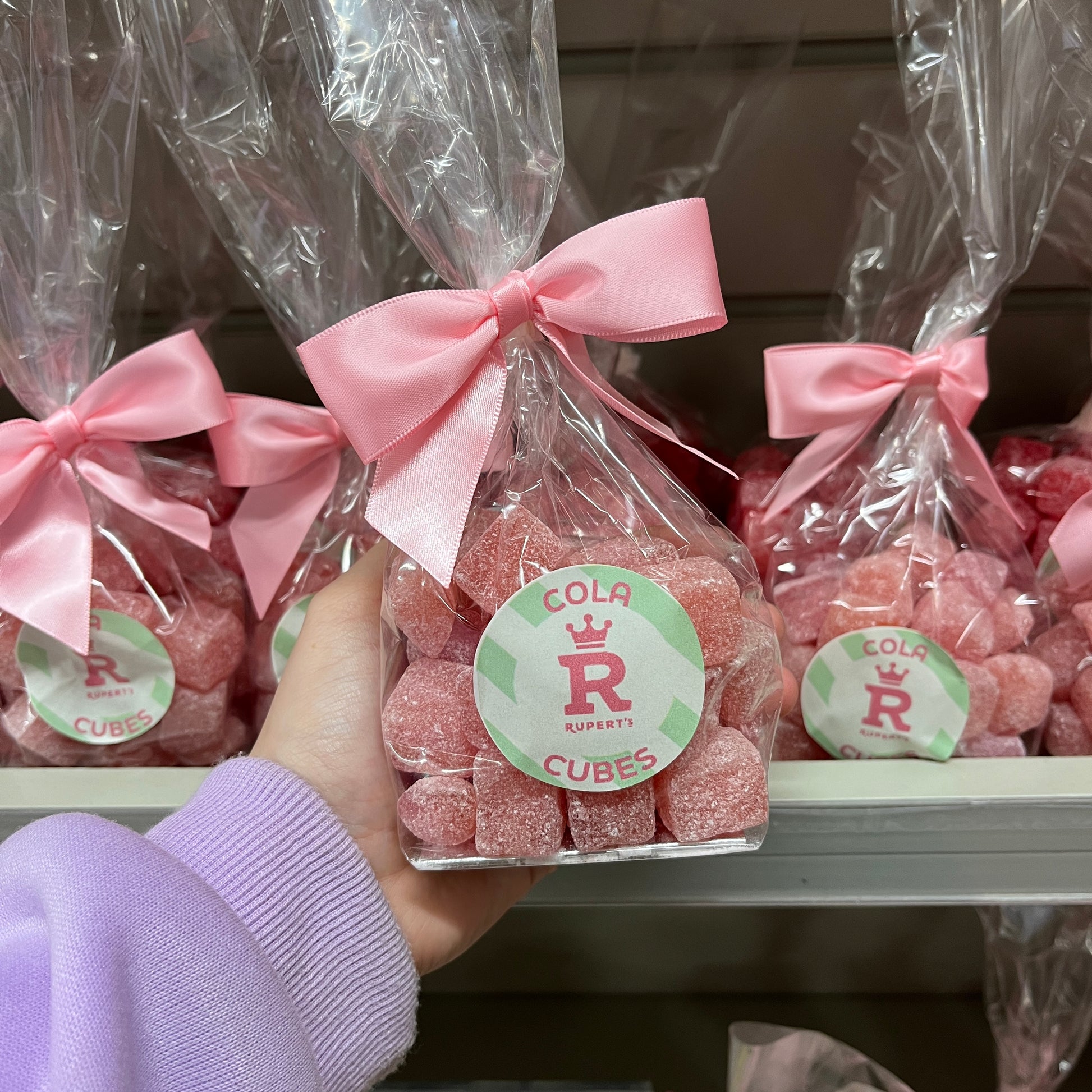 Holding up a small gift bag of cola cubes- Rupert's Candy