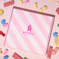 Image of our pink Rupert's Candy box with a variety of pick and mix sweets scattered around it- Rupert's Candy