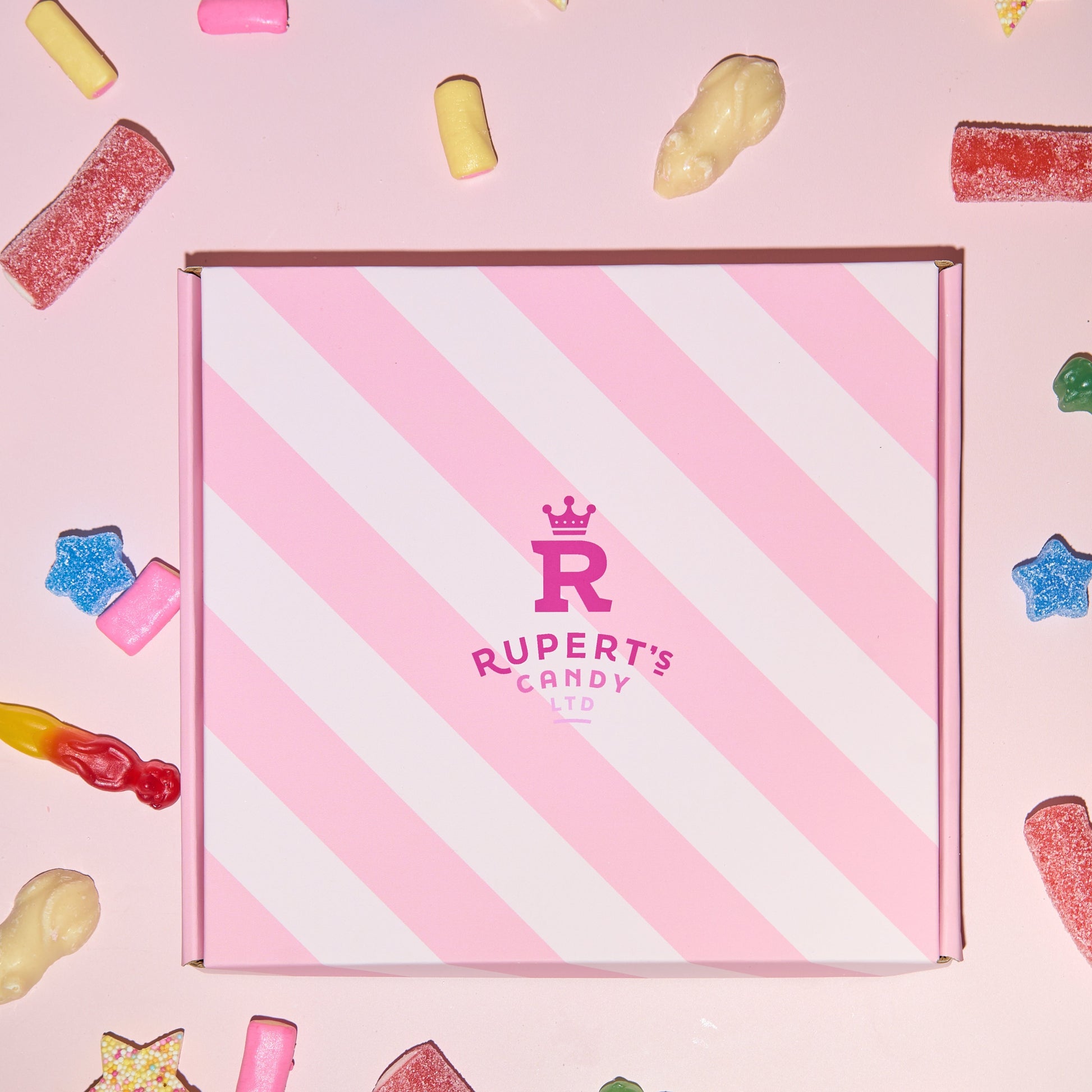 Image of our pink Rupert's Candy box with a variety of pick and mix sweets scattered around it- Rupert's Candy