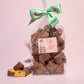 Large gift bag of chocolate cinder toffee with a piece broken up placed next to it- Rupert's Candy