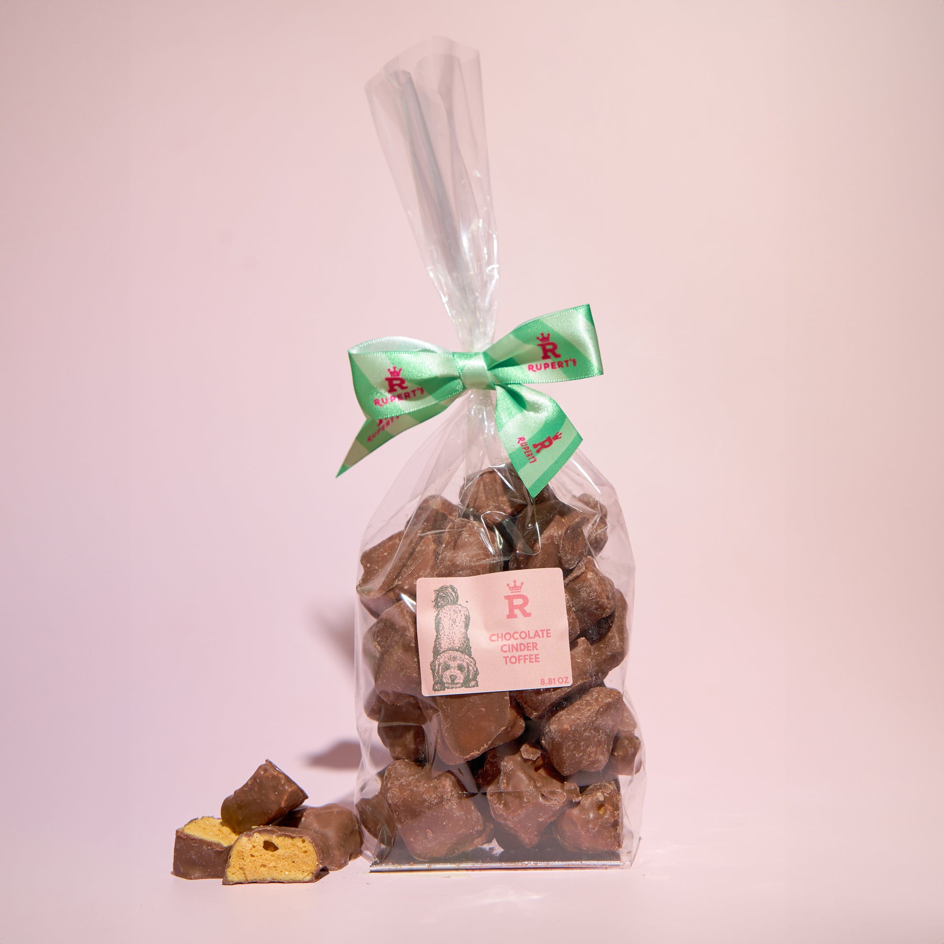 Large gift bag of chocolate cinder toffee with a piece broken up placed next to it- Rupert's Candy