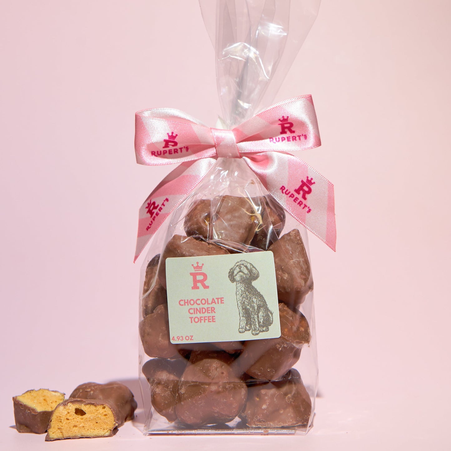 Small gift bag of chocolate cinder toffee with a piece broken up placed next to it- Rupert's Candy