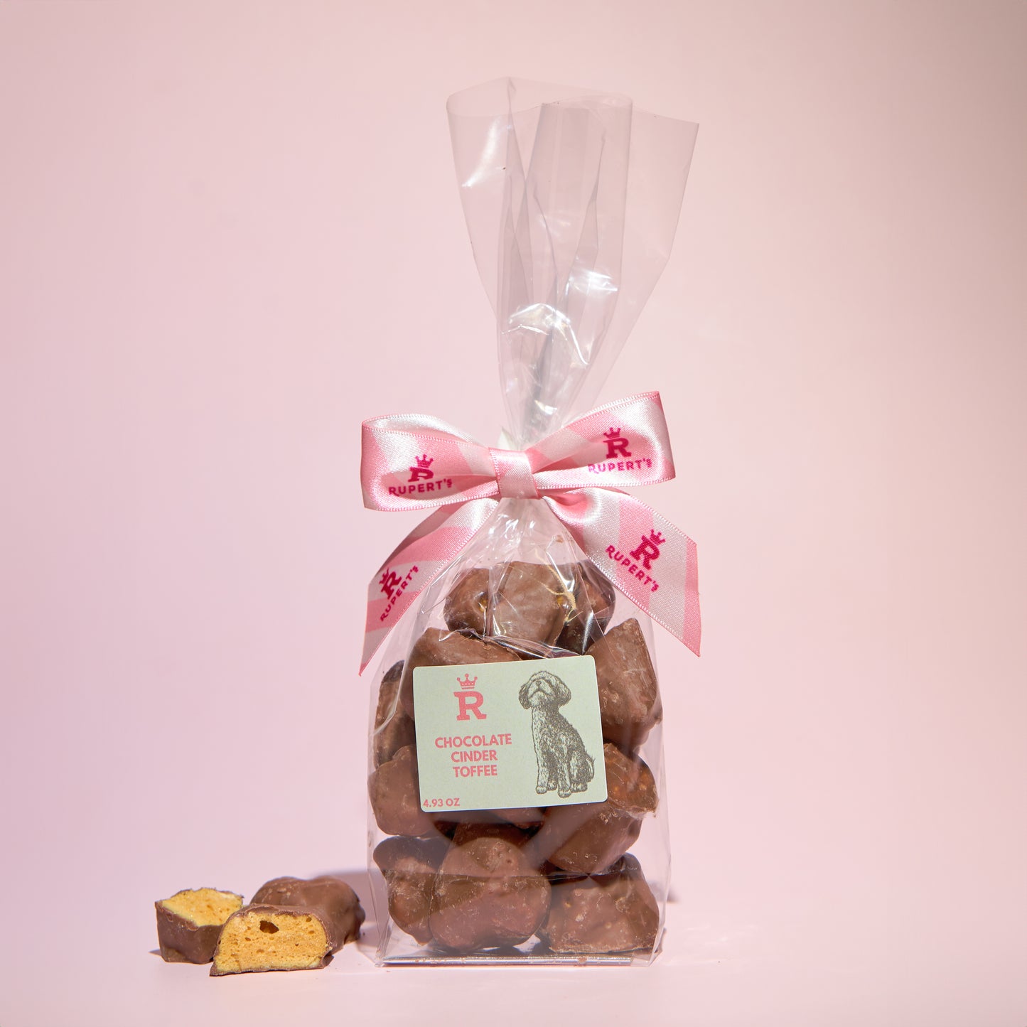 Small gift bag of chocolate cinder toffee with a piece broken up placed next to it- Rupert's Candy