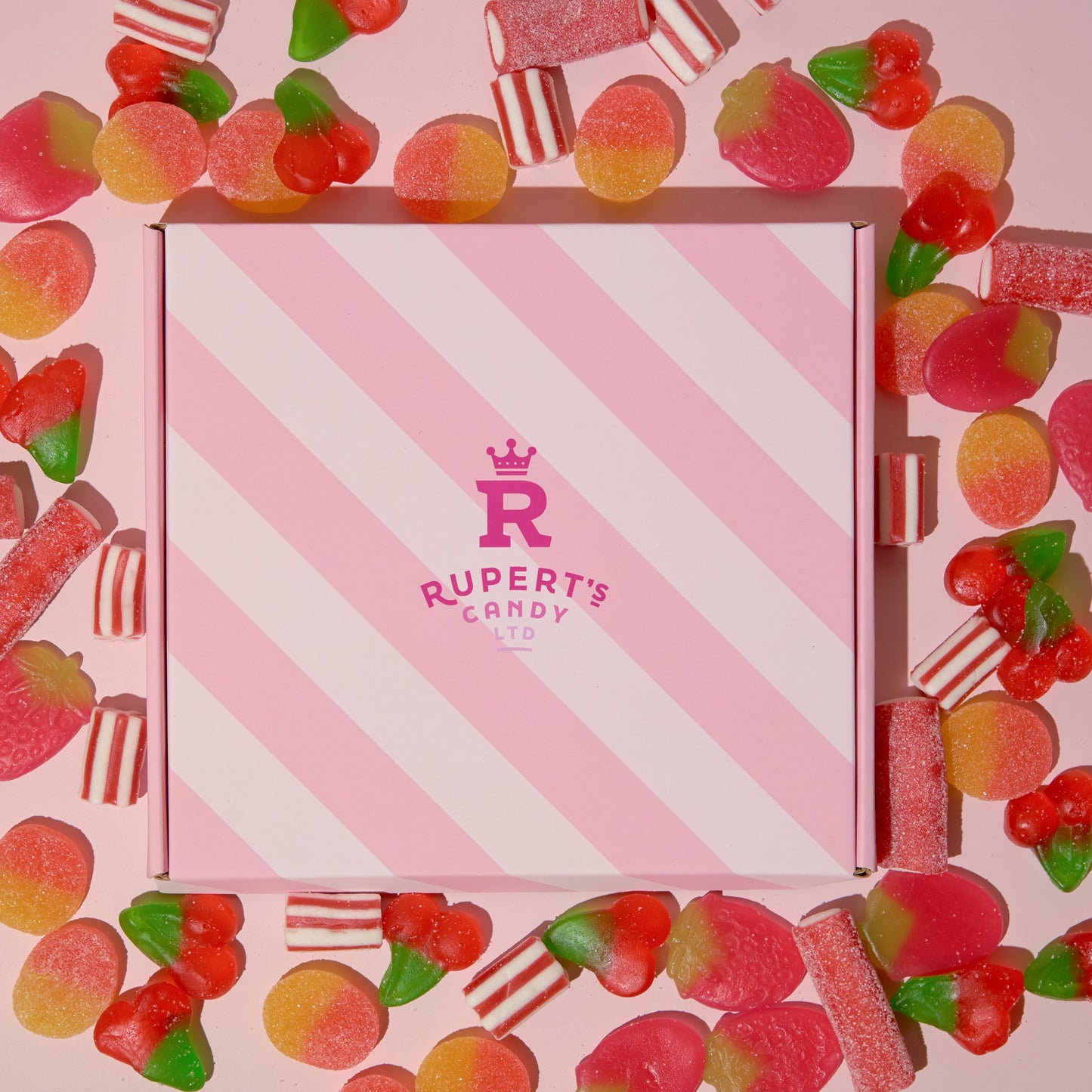 Image of our pink Rupert's Candy box with a variety of red sweets scattered around it- Rupert's Candy